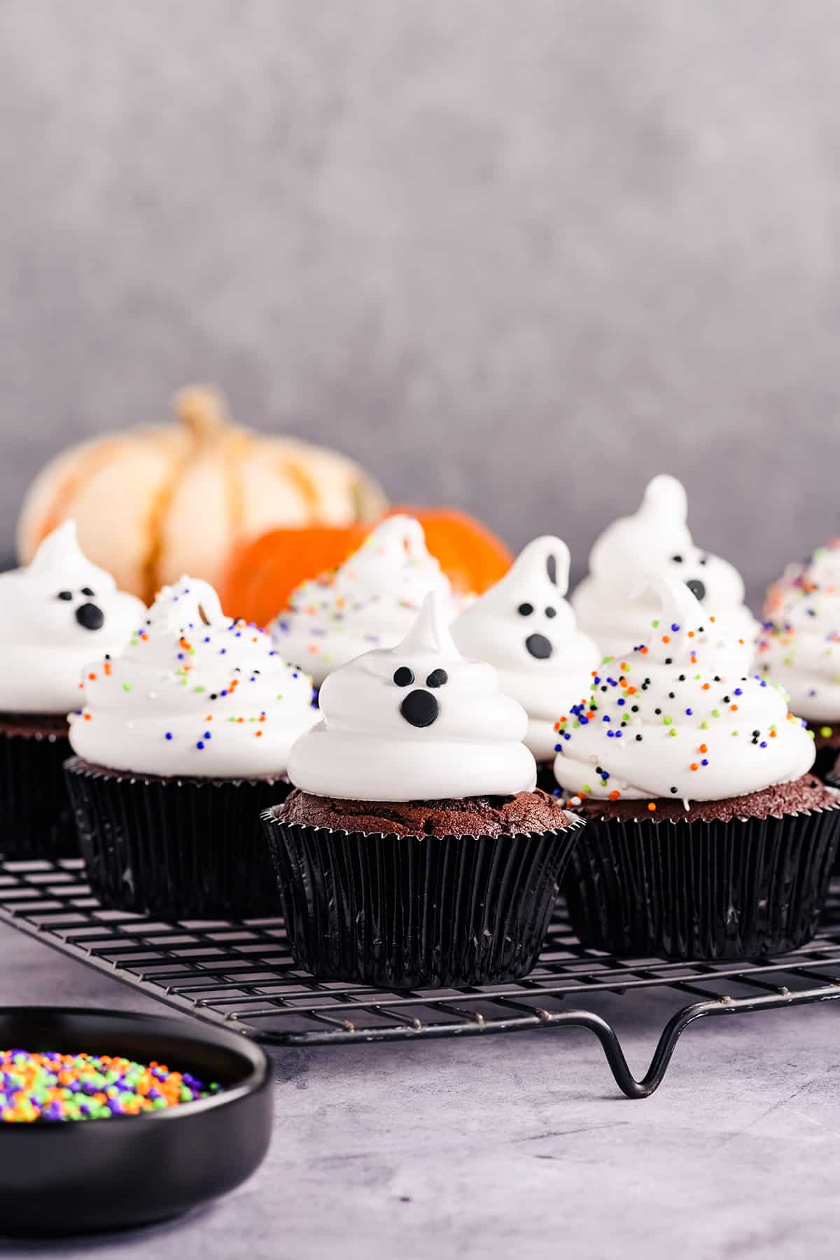 Three quarter angle of Devil's Food Ghost Cupcakes on cooling rack.