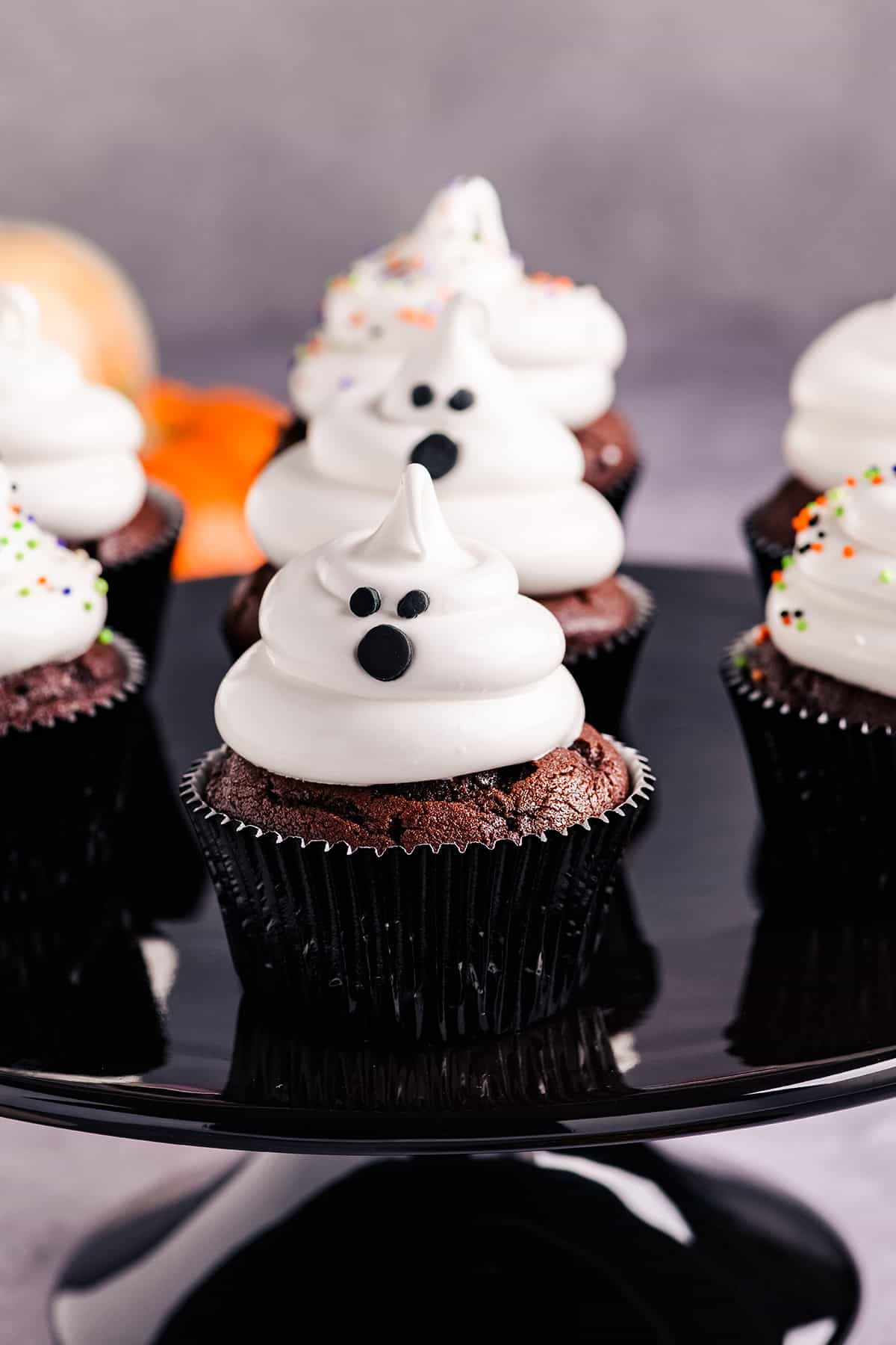 Close up image of Devil's Food Ghost Cupcakes on black cake stand.