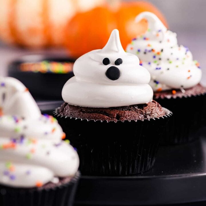 Head on close up of Devil's Food Ghost Cupcakes on black plate.