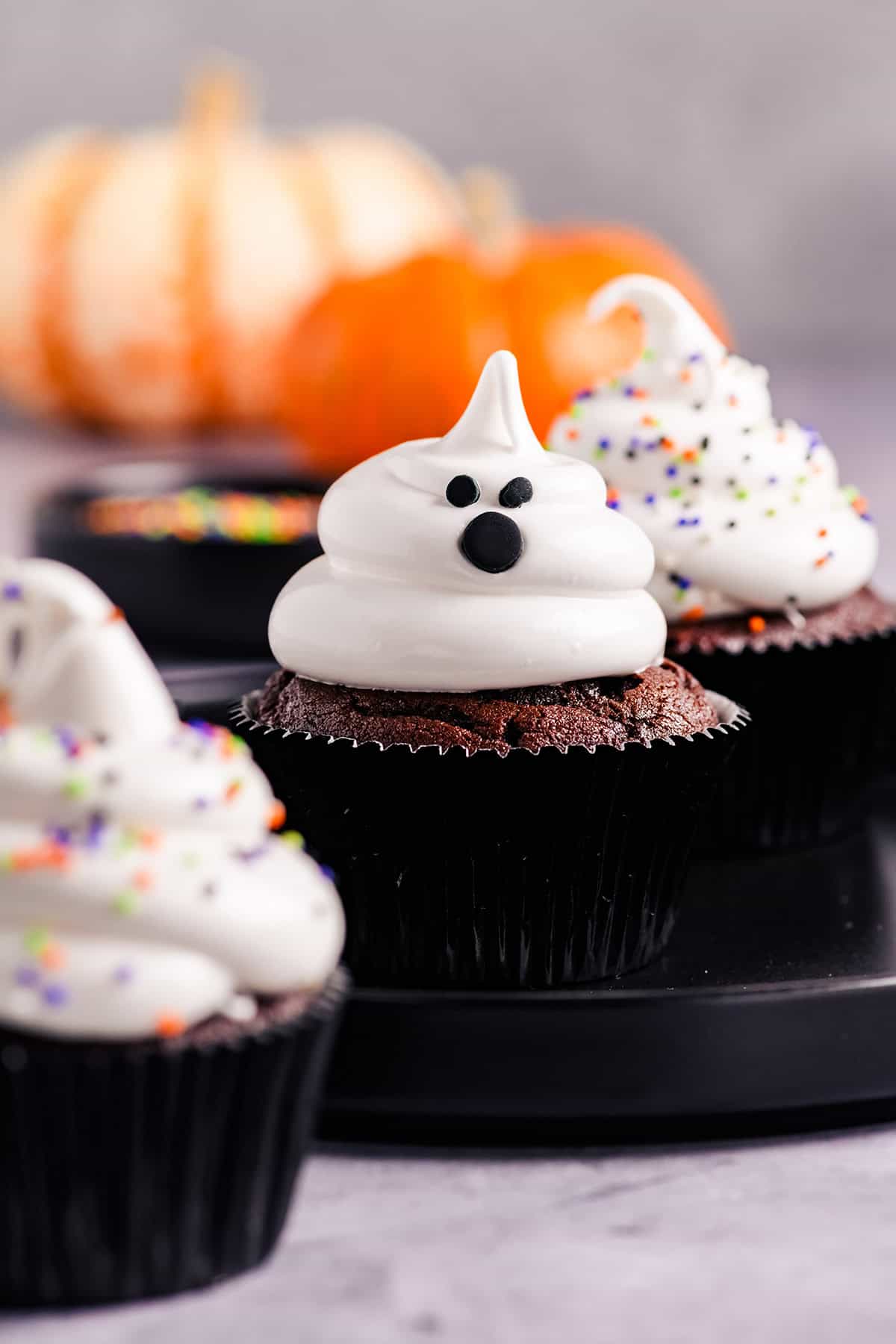 Head on close up of Devil's Food Ghost Cupcakes on black plate.