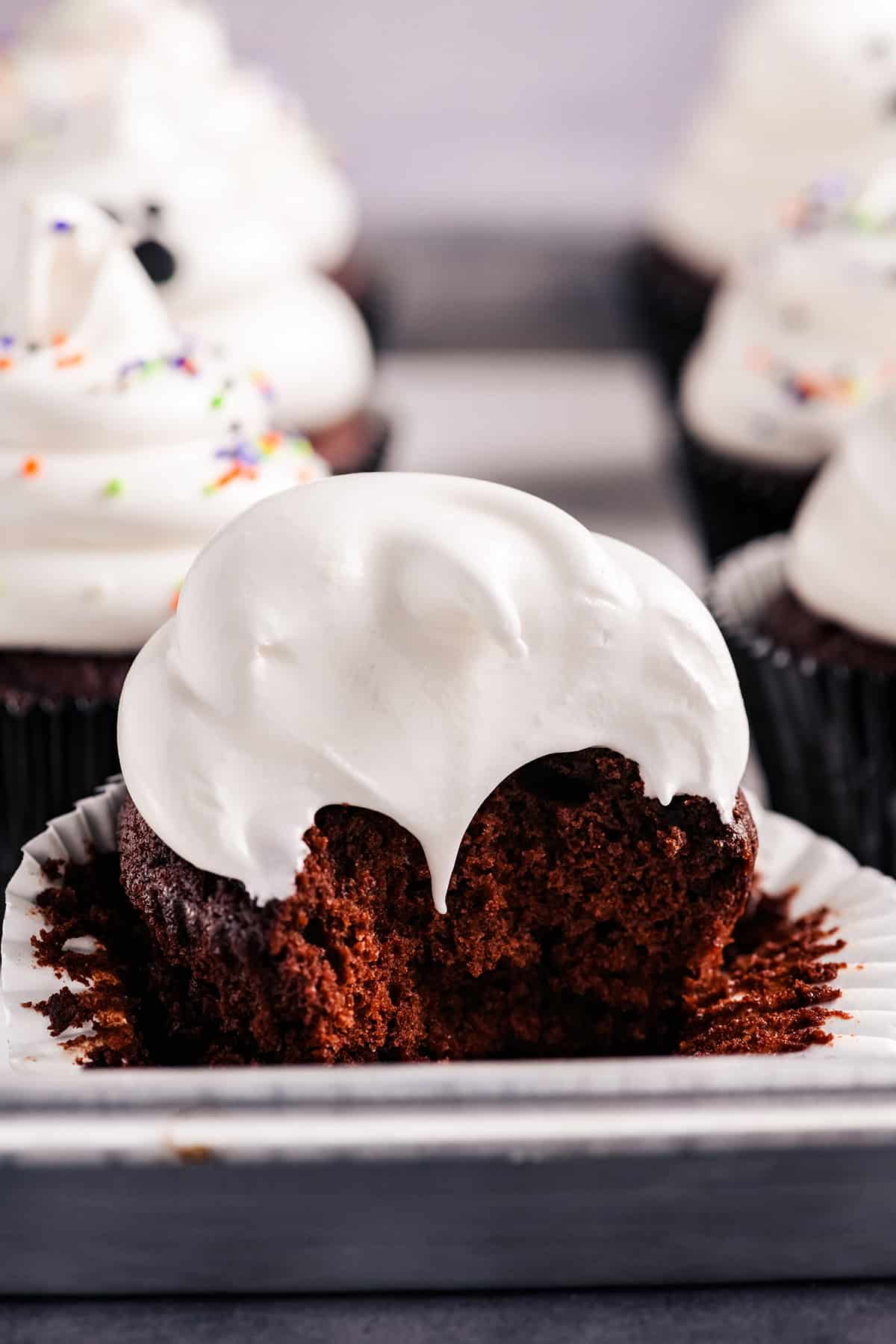 Close up image of bite taken out of Devil's Food Ghost Cupcakes.