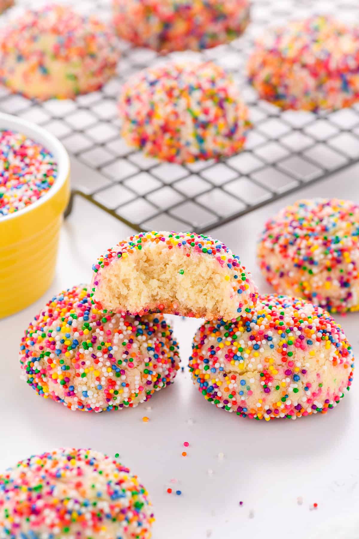 Close up shot of cookie with a bite sitting on a couple of Mexican Sprinkle Cookies.