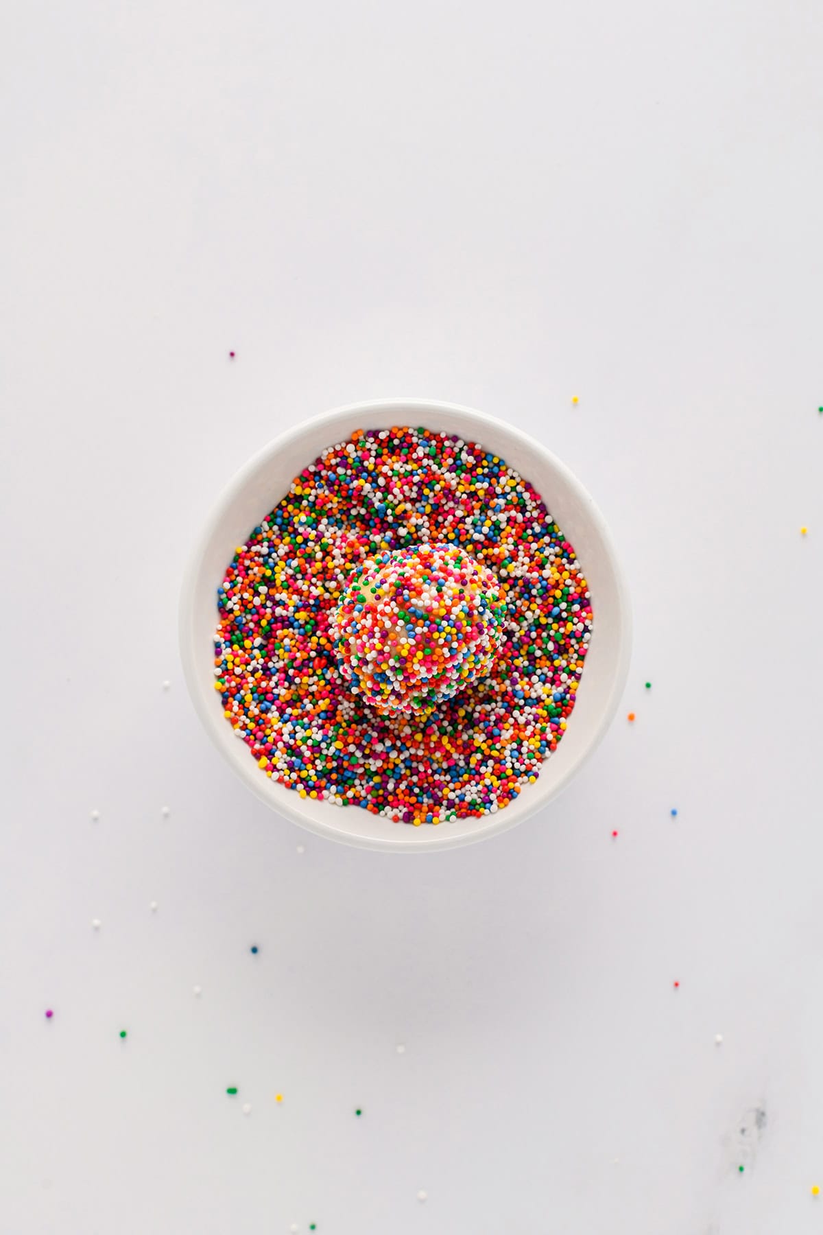 Overhead shot of dough ball covered in sprinkles in the bowl for Mexican Sprinkle Cookies.