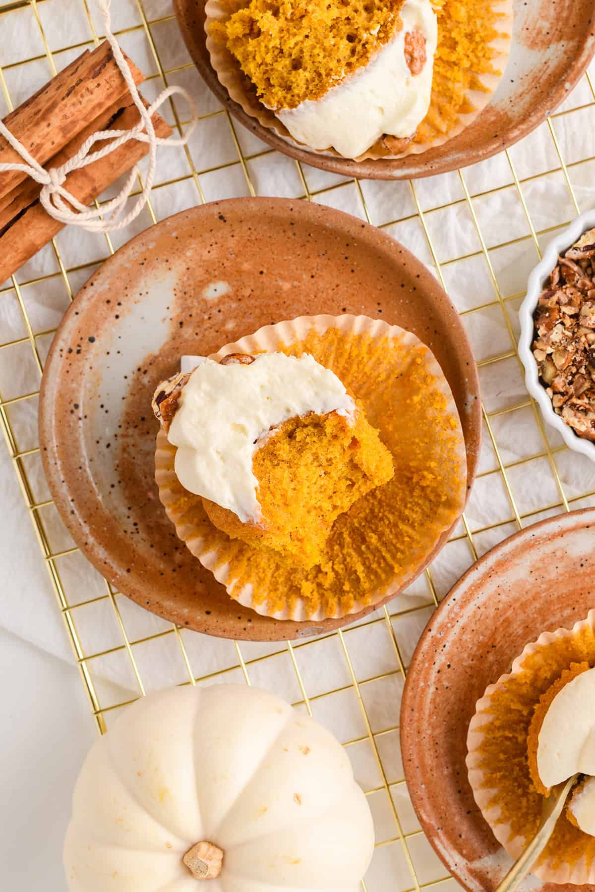 Overhead shot of cut open Pumpkin Cupcakes with Maple Cream Cheese Frosting on top of a gold cooling rack.