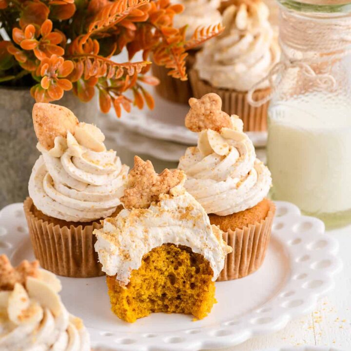 Three Pumpkin Pie Cupcakes on a white plate with bite and milk bottle.