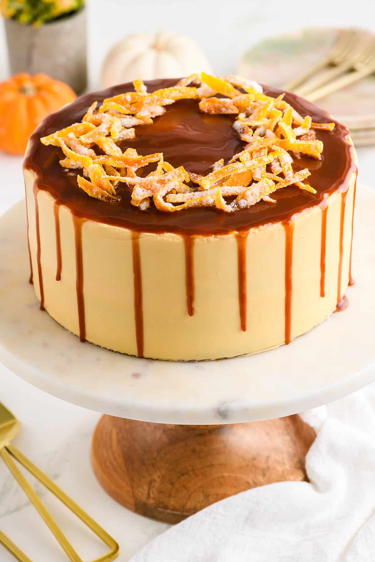 Pumpkin Spice Layer Cake with Caramel Cream Cheese Frosting on a marble and wood cake stand.