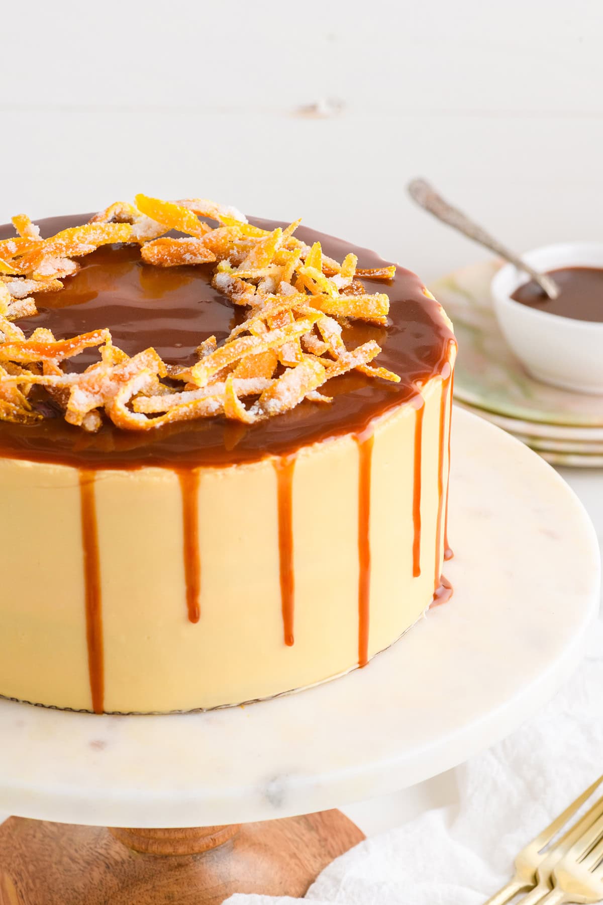 Close up shot of the top of Pumpkin Spice Layer Cake with Caramel Cream Cheese Frosting focusing on the caramel drip and candied orange peel.