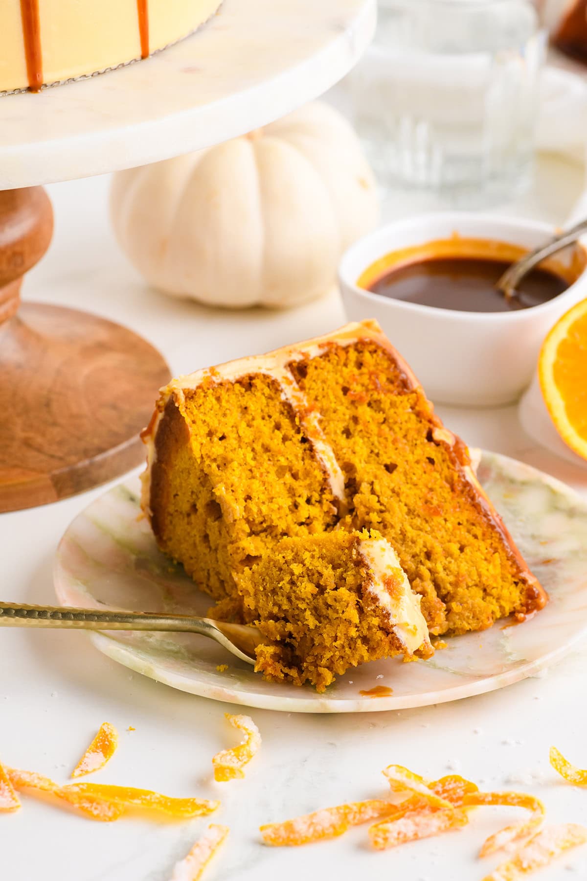 Three quarter angle of sliced Pumpkin Spice Layer Cake with Caramel Cream Cheese Frosting on a plate with fork.