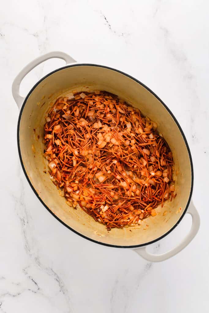Overhead shot of fried fideo, onions and garlic with tomato paste, chipotle pepper, and oregano for Chicken Fideo Soup.