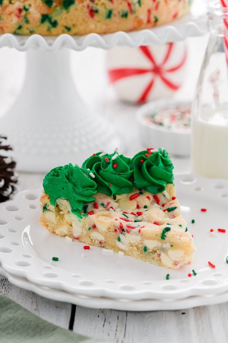 Close up slice of Christmas Confetti Cookie Cake on white plate.