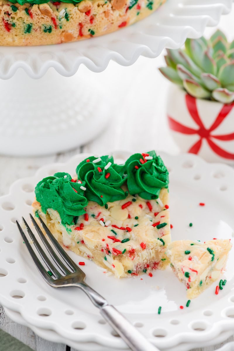 Close up angled shot of sliced and cut Christmas Confetti Cookie Cake with fork on white plate.