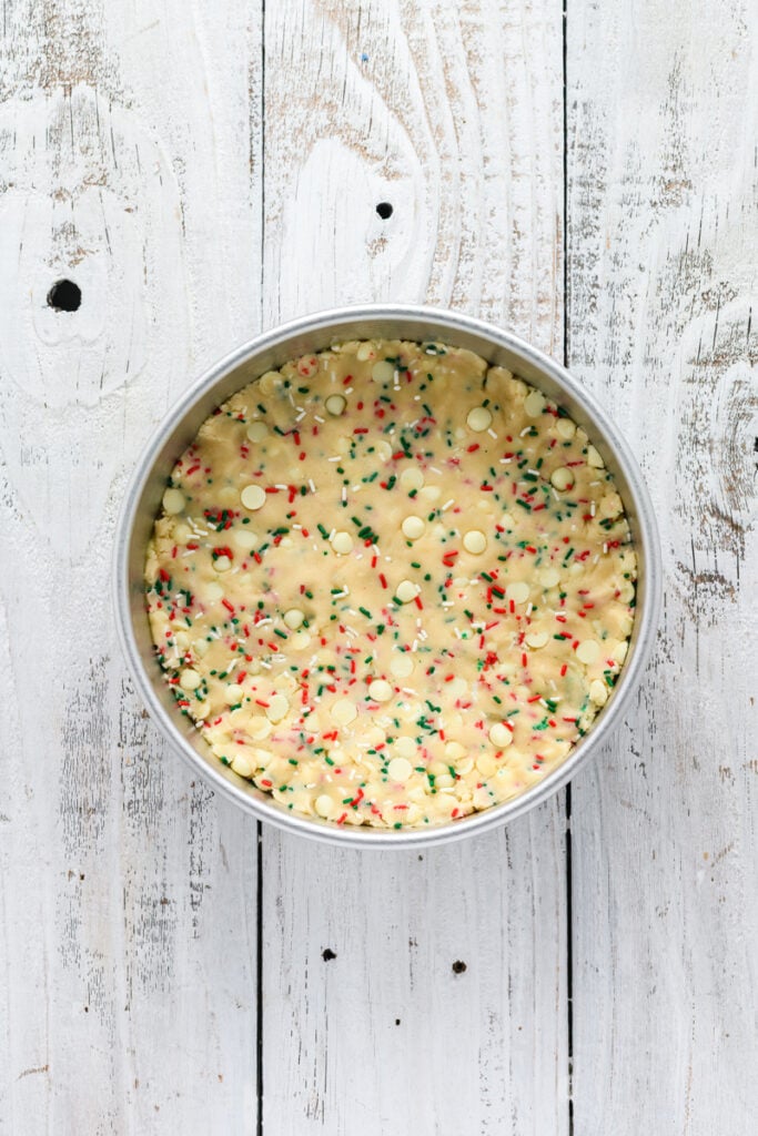 Overhead shot of Christmas Confetti Cookie Cake dough in cake pan.