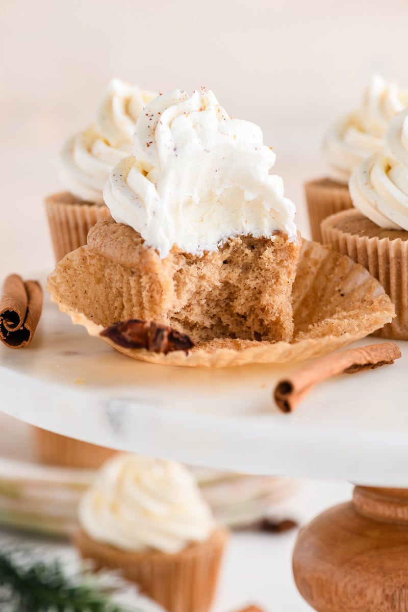Close up shot of a bitten Eggnog Cupcake on cake pedestal.