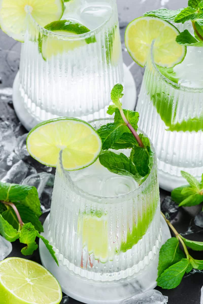 Angled shot of refreshing Hangover Cures with ice and mint on work surface.