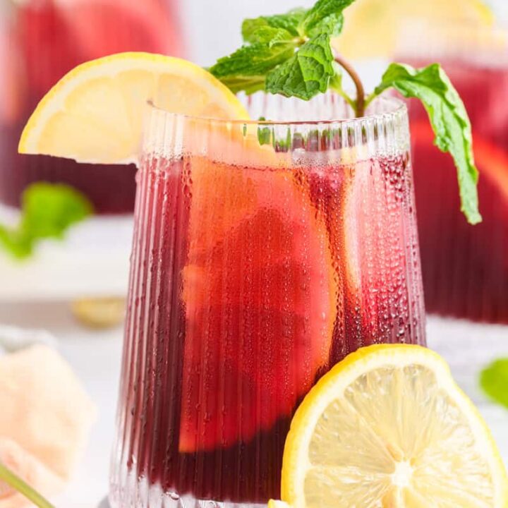 Close up shot of a glass of Simple Sangria garnished with a lemon slice and fresh mint.