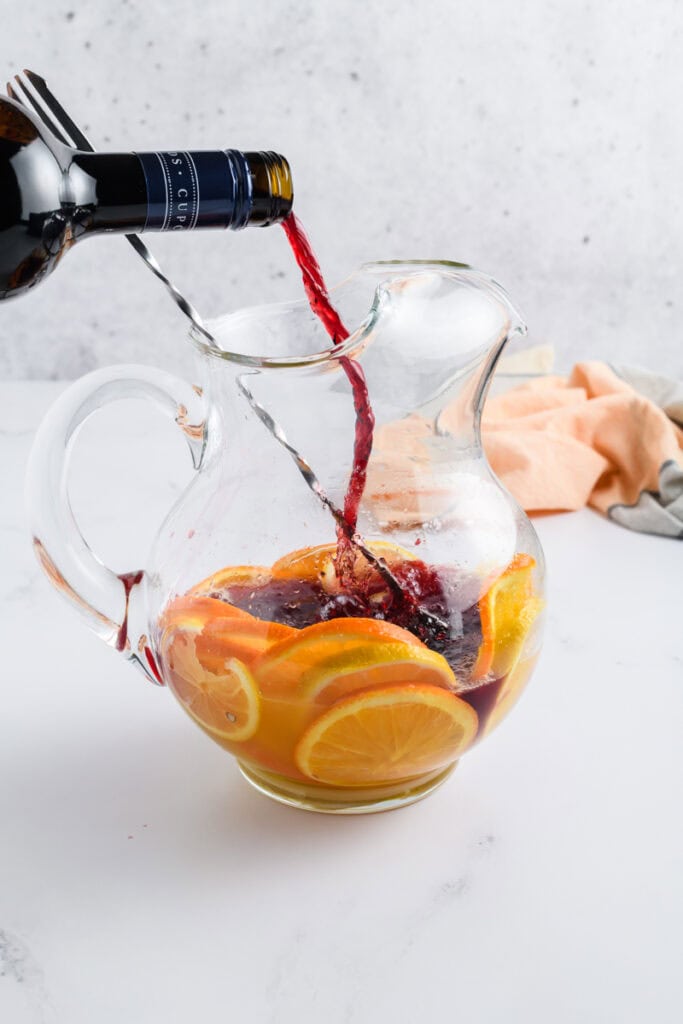 Process shot of wine being poured into pitcher for Simple Sangria.