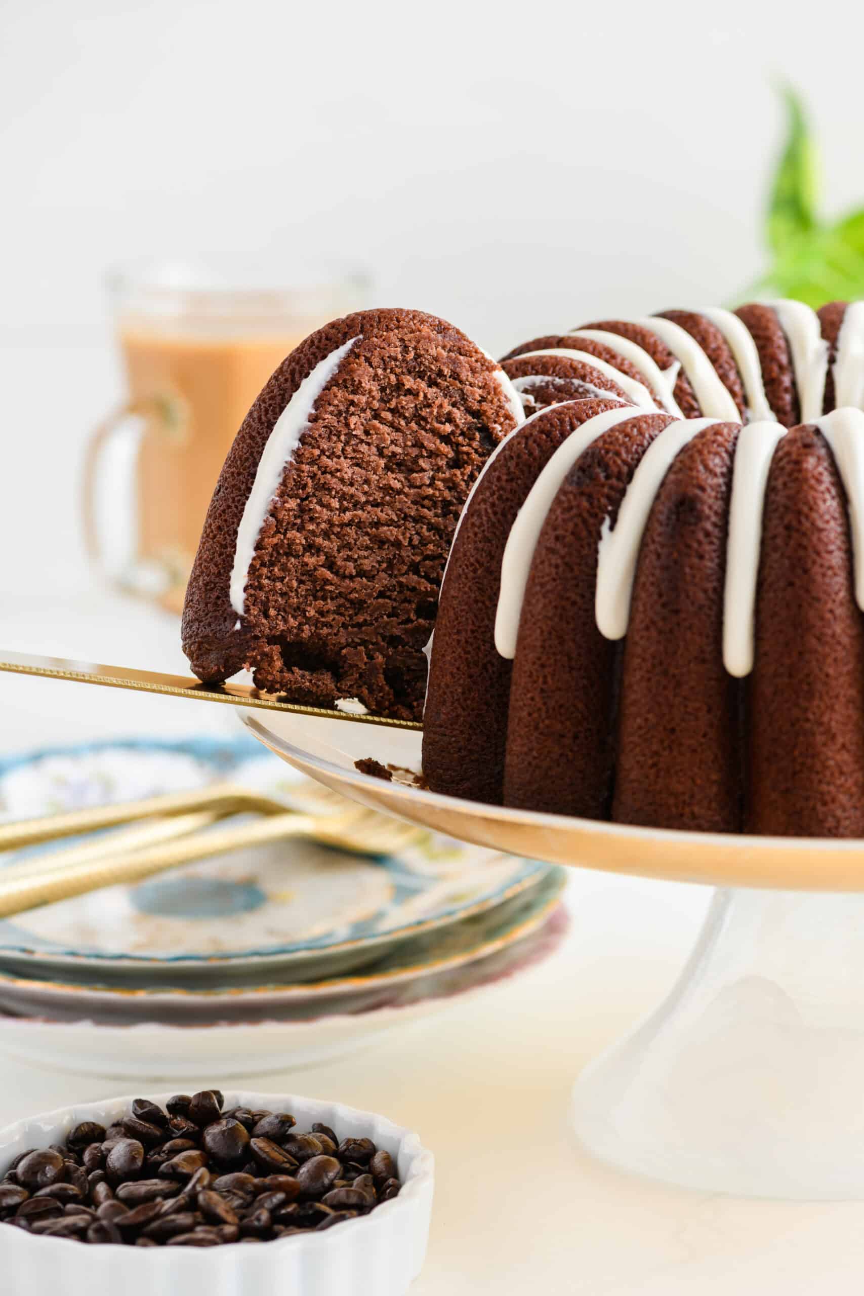 Healthier Chocolate Coffee Cake being sliced on cake stand with slice pulled out.