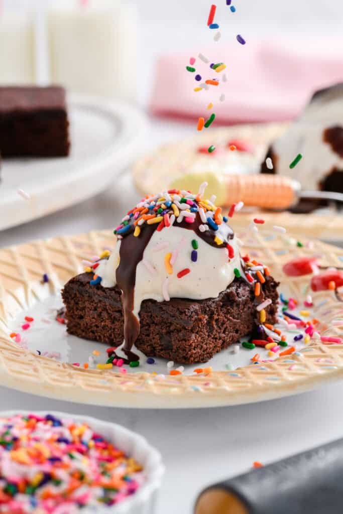 Close up shot of sprinkles being poured on top of Lightened Up Brownie a la Mode.