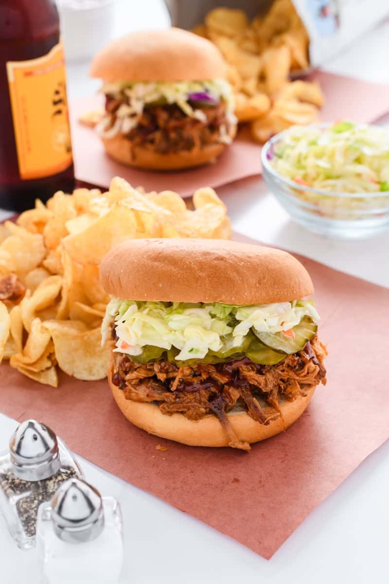 Angled shot of Slow Cooker Pulled Pork Sandwiches with bottle of beer.