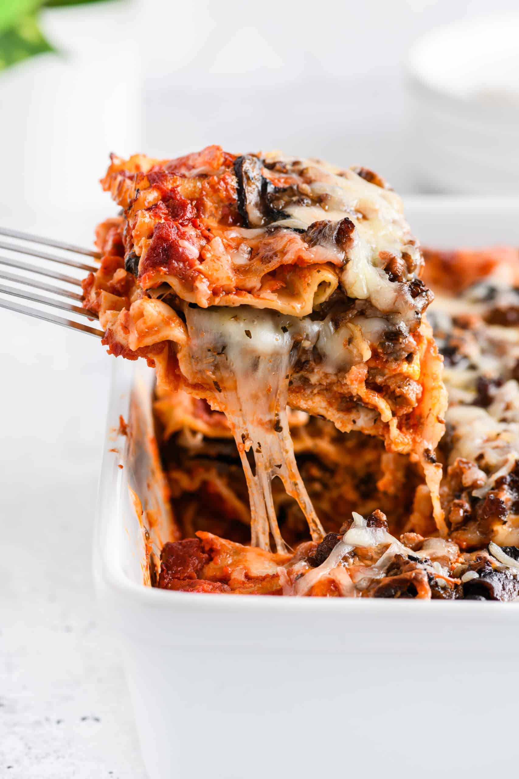 Close up shot of cheese pull for Easy Sausage and Mushroom Lasagna.