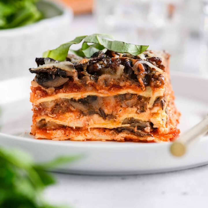 Close up shot of sliced Easy Sausage and Mushroom Lasagna on white serving plate.