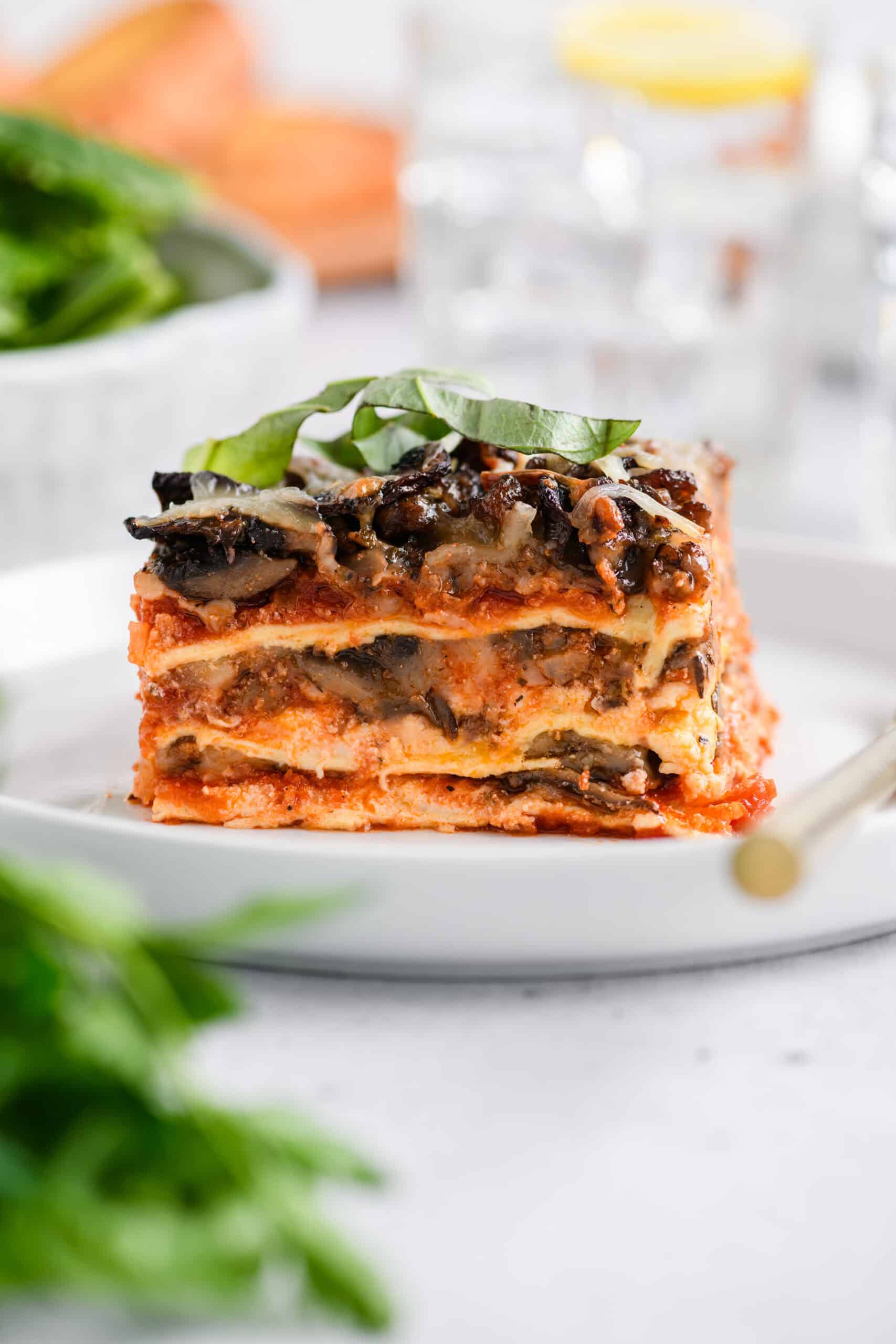 Close up shot of sliced Easy Sausage and Mushroom Lasagna on white serving plate.