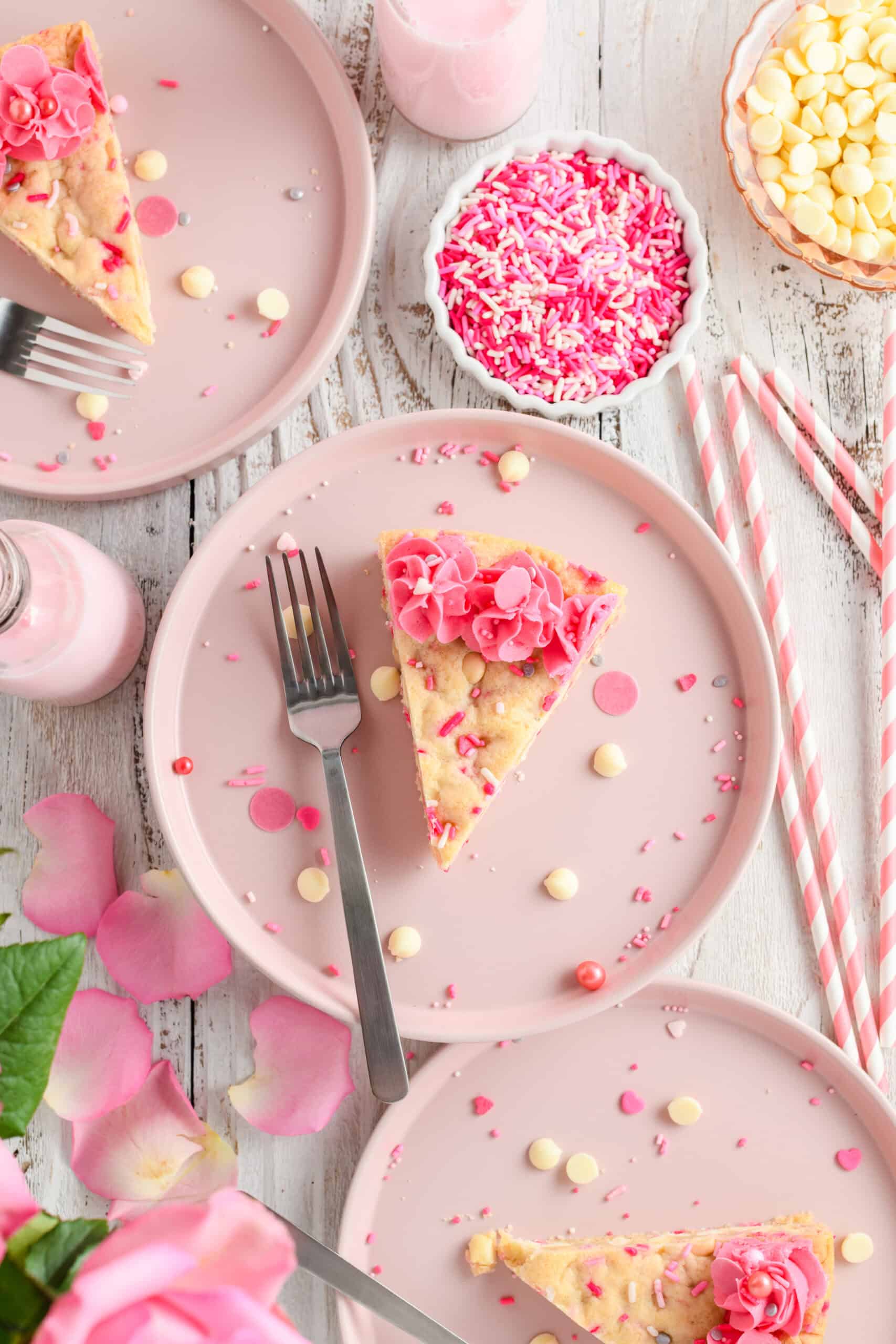 Overhead shot of several slices of Valentine Confetti Cookie Cake on pink plates.