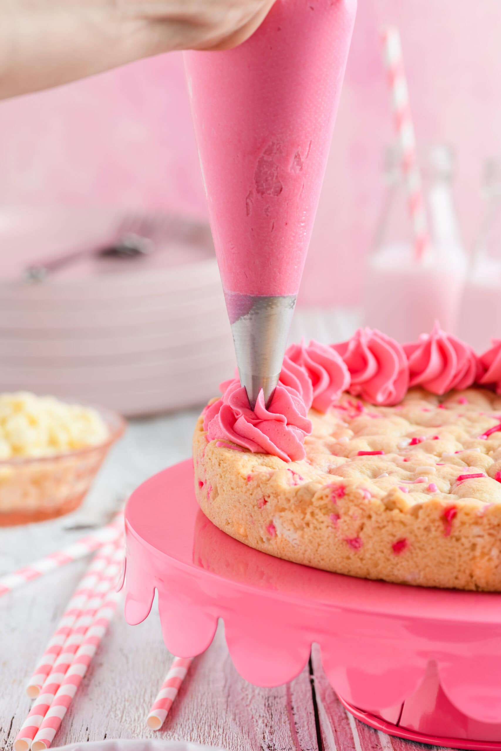 Buttercream being piped onto Valentine Confetti Cookie Cake.
