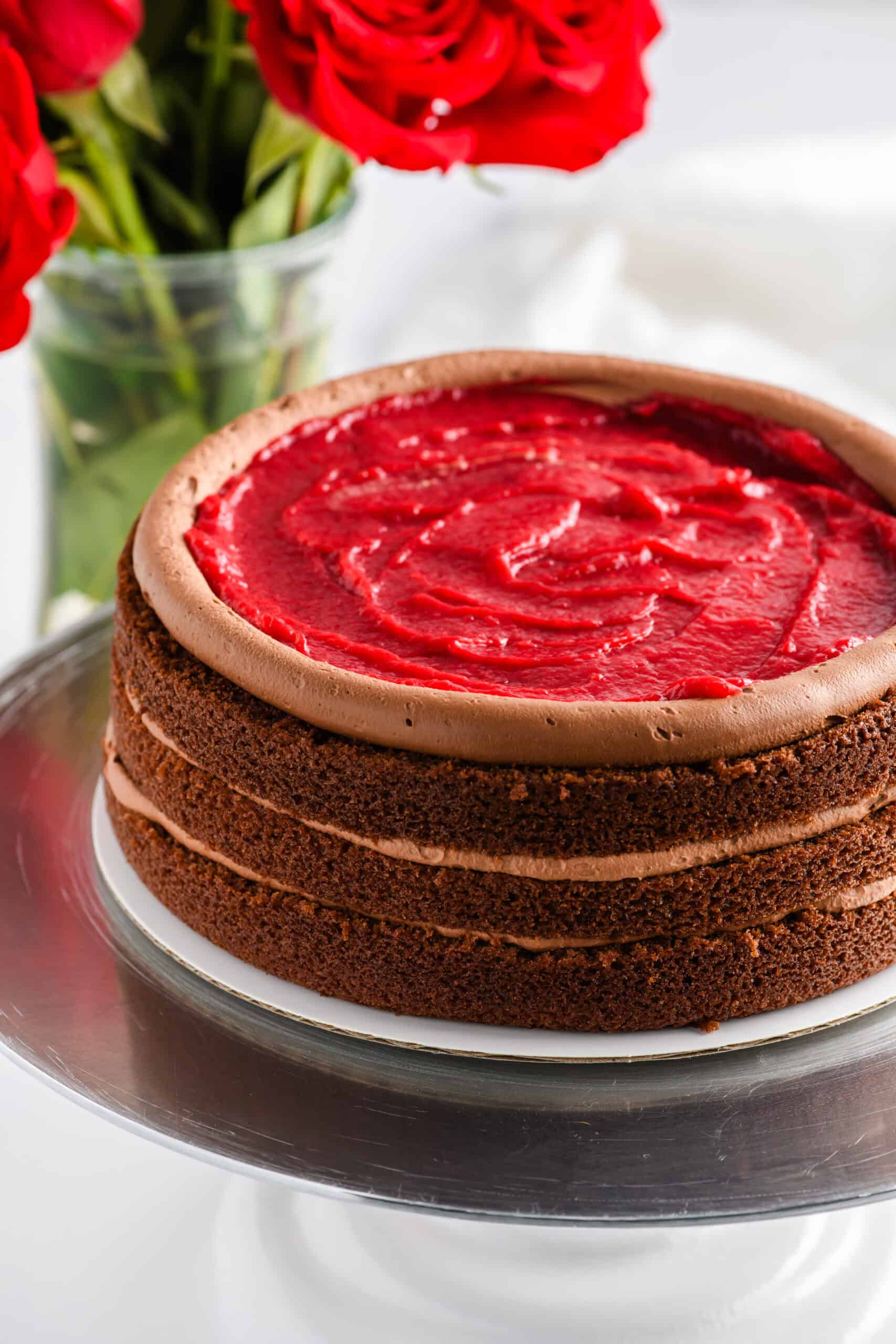 Angled shot of Chocolate Raspberry Cake with Whipped Ganache Frosting filling process.