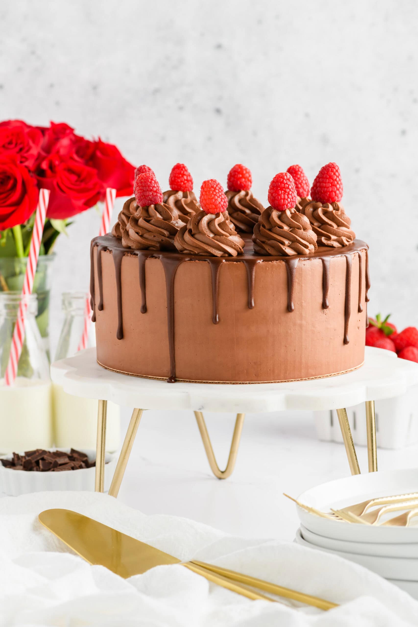 Whole Chocolate Raspberry Cake with Whipped Ganache Frosting on marble cake stand.