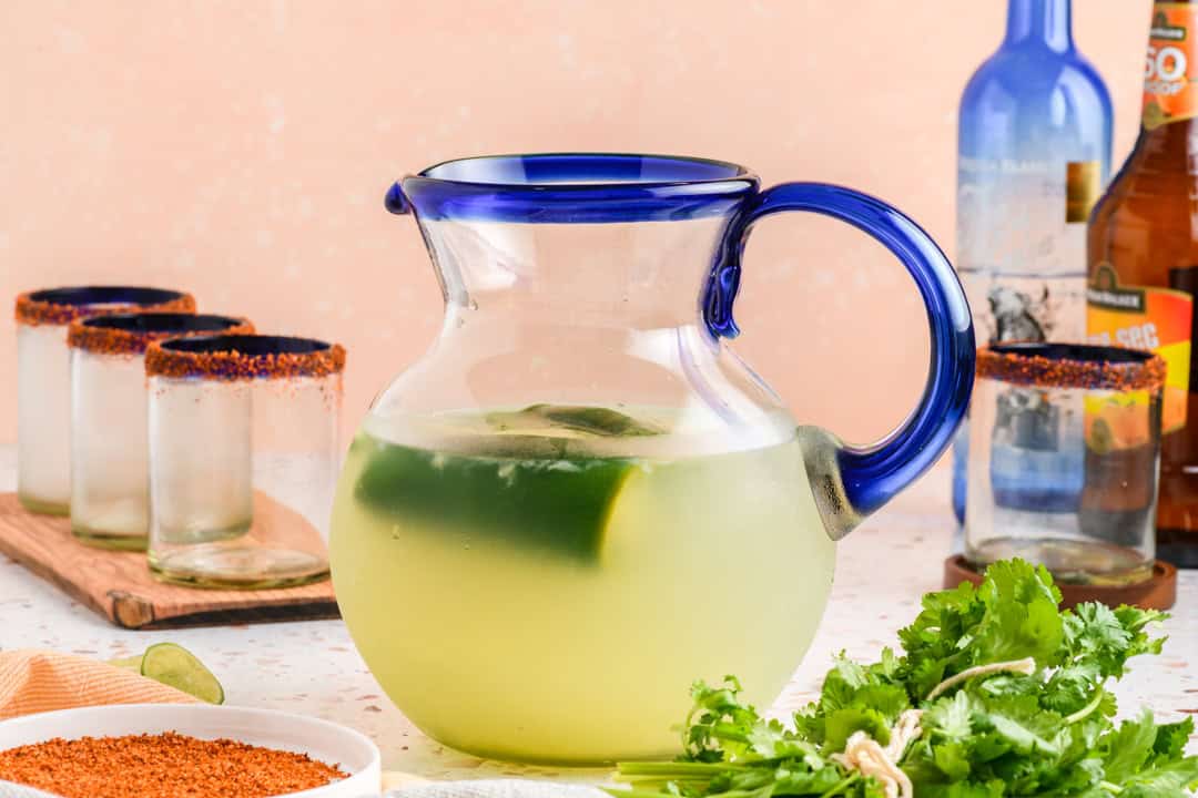Jalapeno Margaritas in pitcher, with glasses ready to serve nearby.