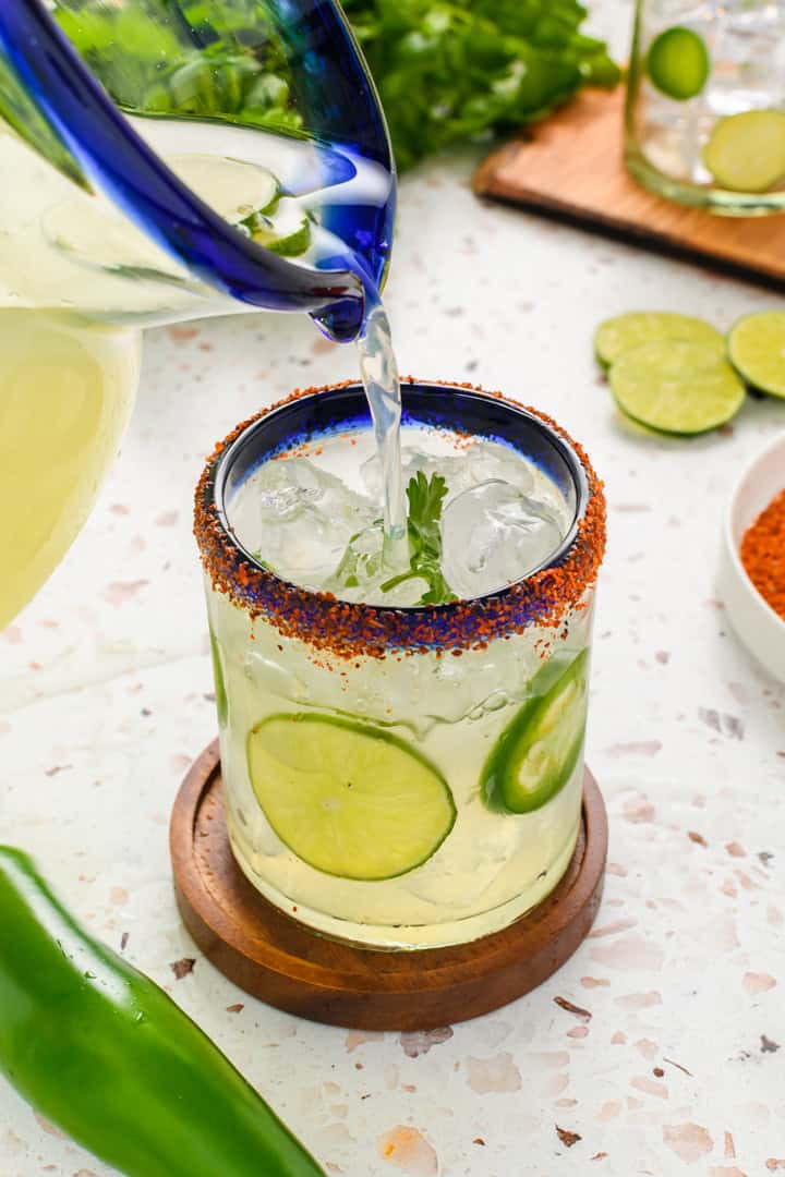 Angled shot of pouring Jalapeño Margarita into glass.