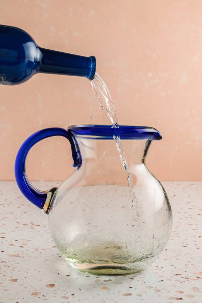 Process shot of tequila going in the pitcher for Jalapeño Margaritas.