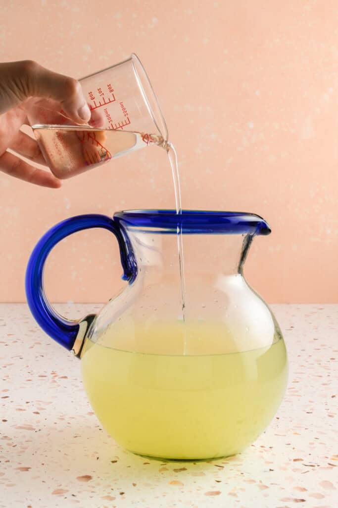 Process shot of simple syrup going into the pitcher for Jalapeño Margaritas.