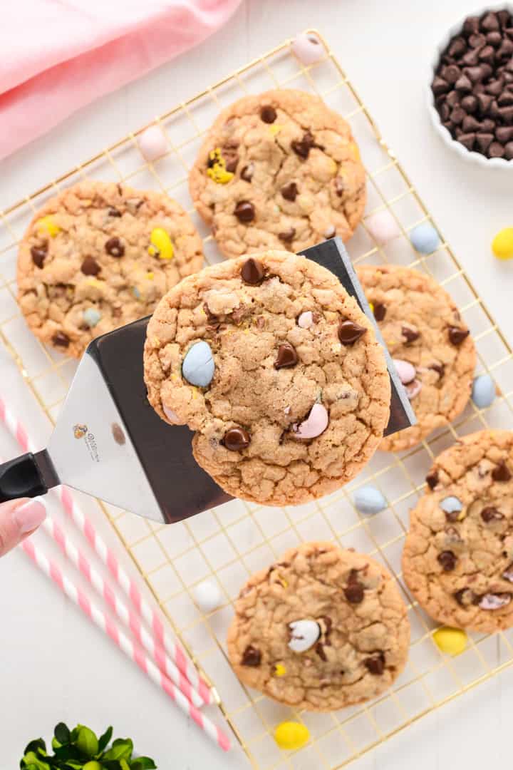 Overhead shot of Easy Easter Chocolate Chip Cookies on gold cooling rack with cookie spatula lifting up one cookie.