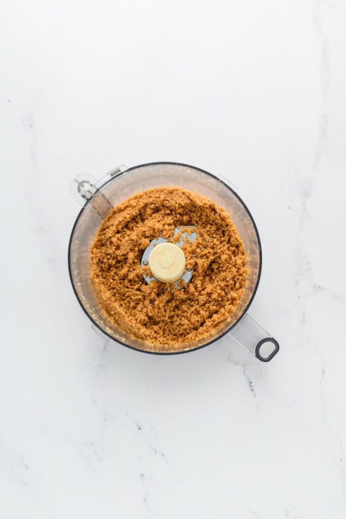 Overhead shot of graham cracker mixture in processor bowl for Key Lime Pie.