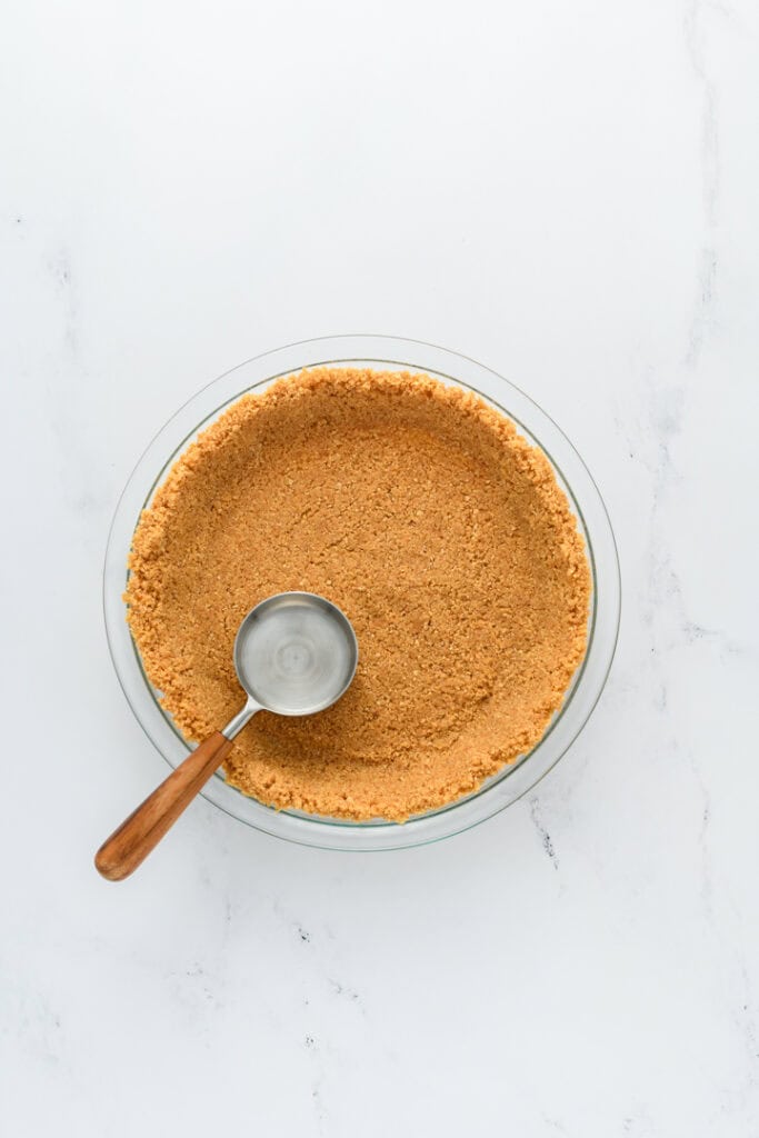 Overhead shot of cookie crust in pie plate for Key Lime Pie.