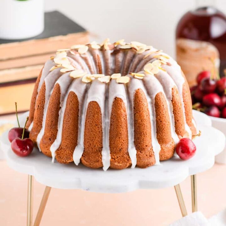 Whole Amaretto Bundt Cake on marble cake stand at slight angle.
