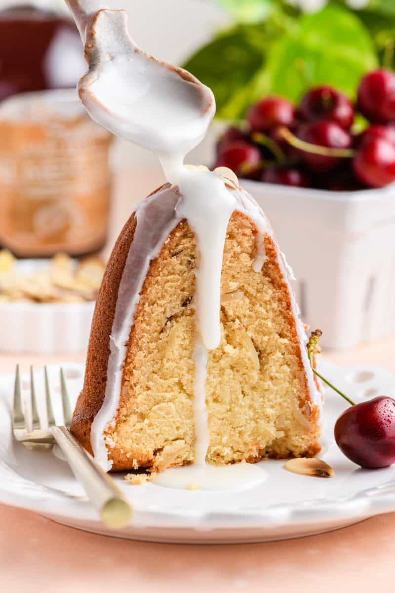 Close up of Amaretto Bundt Cake slice with glaze being drizzled on top.