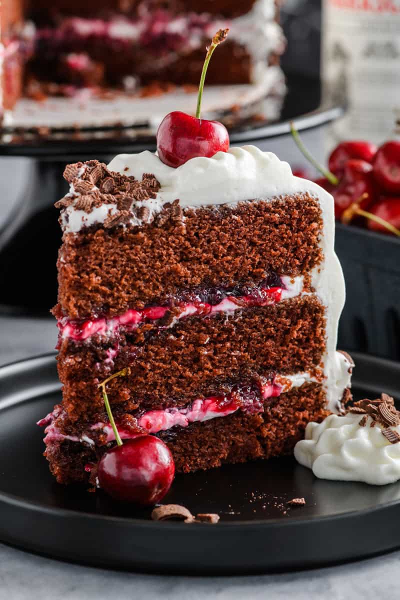 Macro shot of slice of Black Forest Cake on black plate.