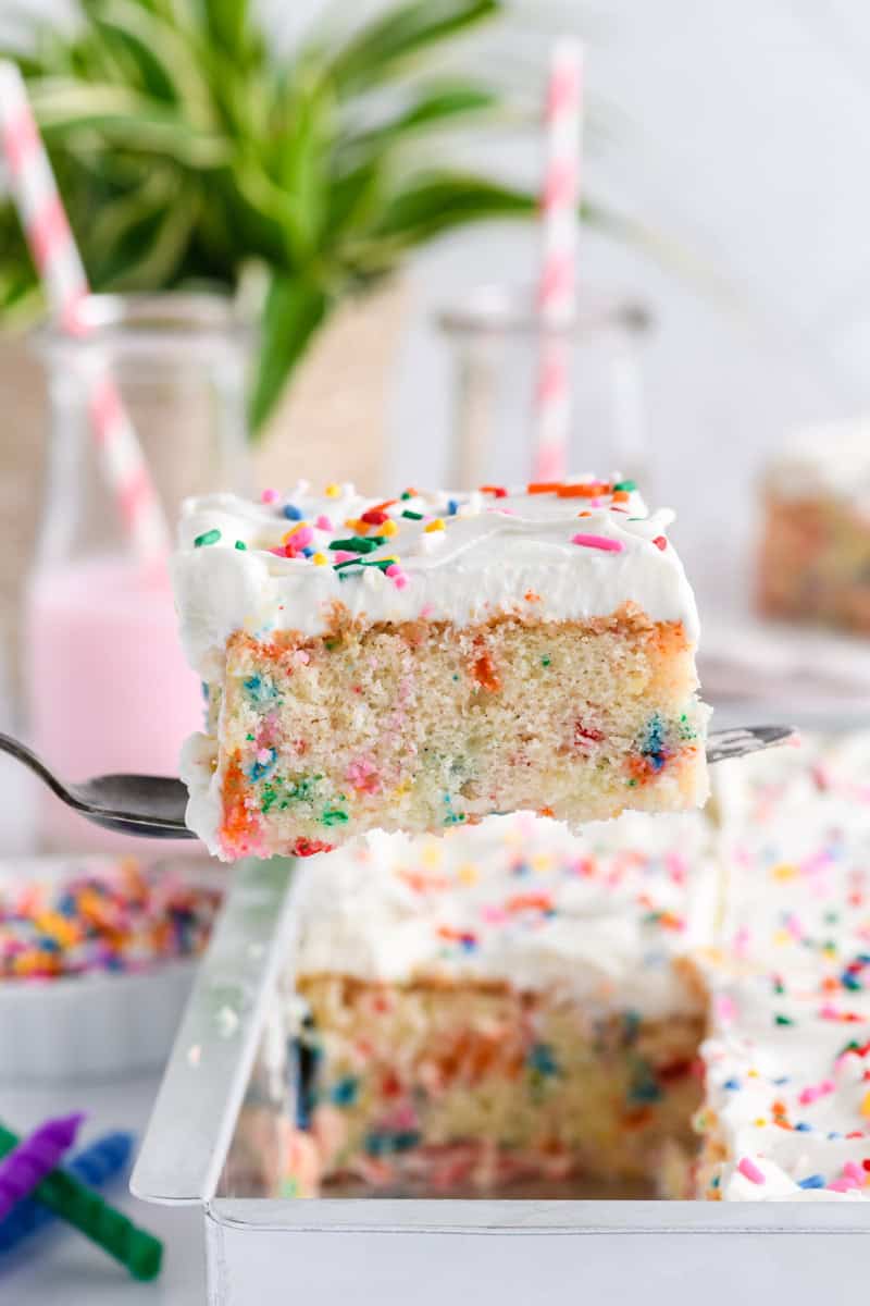 Sliced piece of Funfetti Sheet Cake getting pulled up with a cake server.