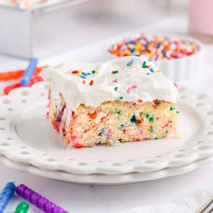 Angled close up shot of a slice of Funfetti Sheet Cake on a white plate.