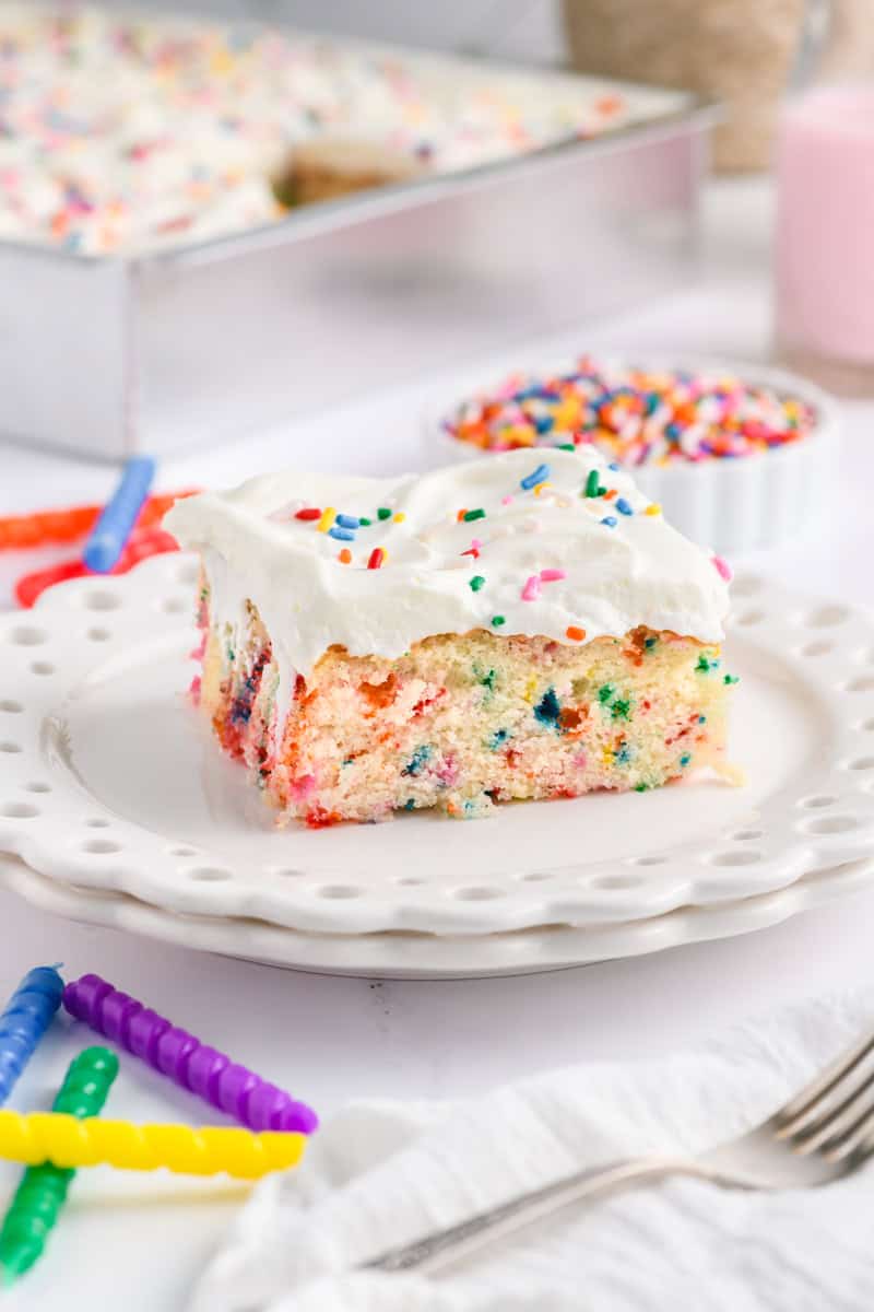 Angled close up shot of a slice of Funfetti Sheet Cake on a white plate.