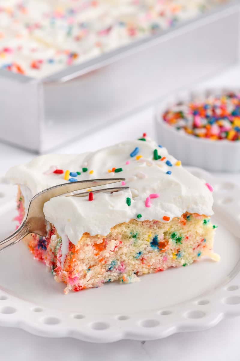 Angled shot of fork cutting through slice of Funfetti Sheet Cake.