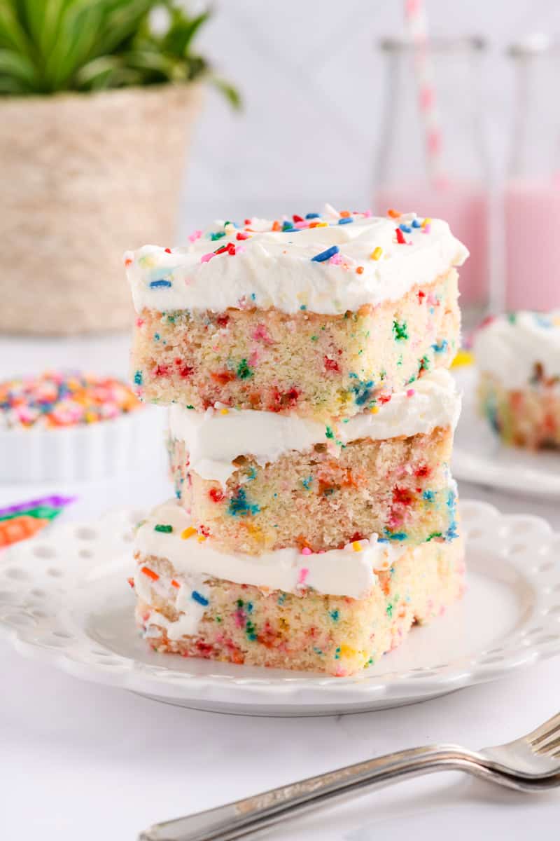 Three stacked slices of Funfetti Sheet Cake on white plate.