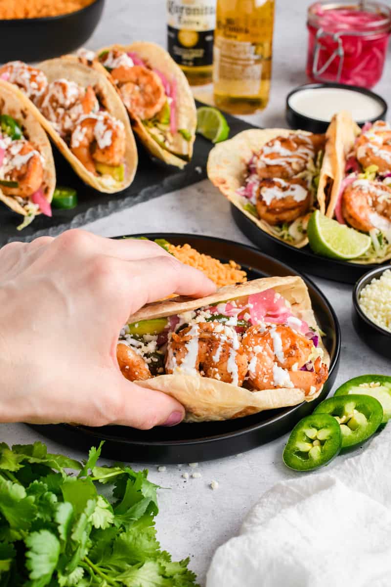 Angled shot of hand grabbing one Easy Shrimp Taco.