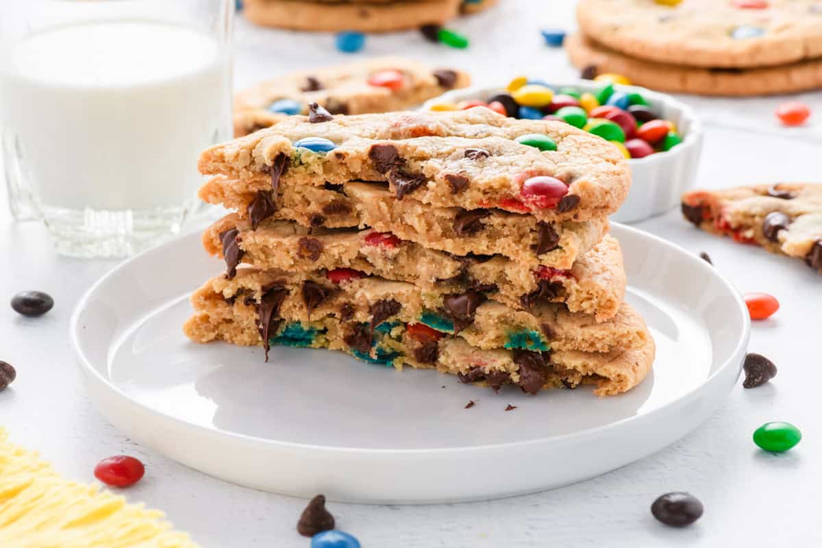 Close up shot of stack of Best Big Fat Chewy M&M Cookies cut open on plate.