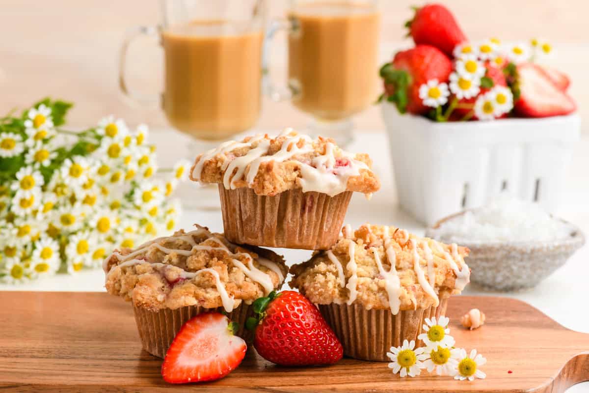 Angled shot of 3 stacked Homemade Strawberry Muffins on wood board.