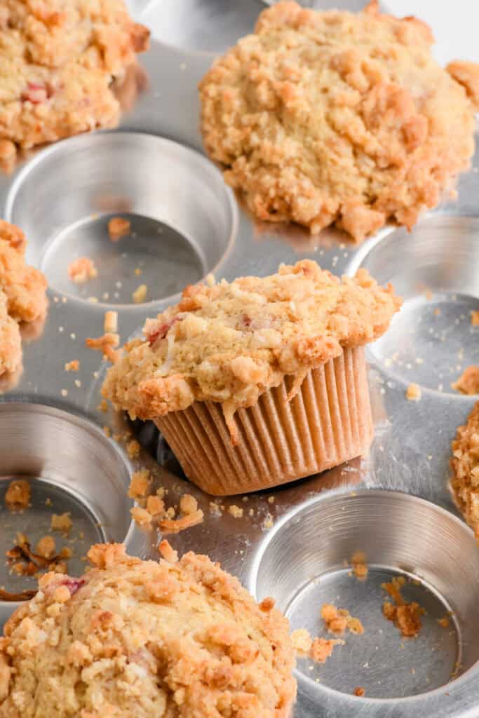 Angled shot of baked Homemade Strawberry Muffins popping out of muffin pan.