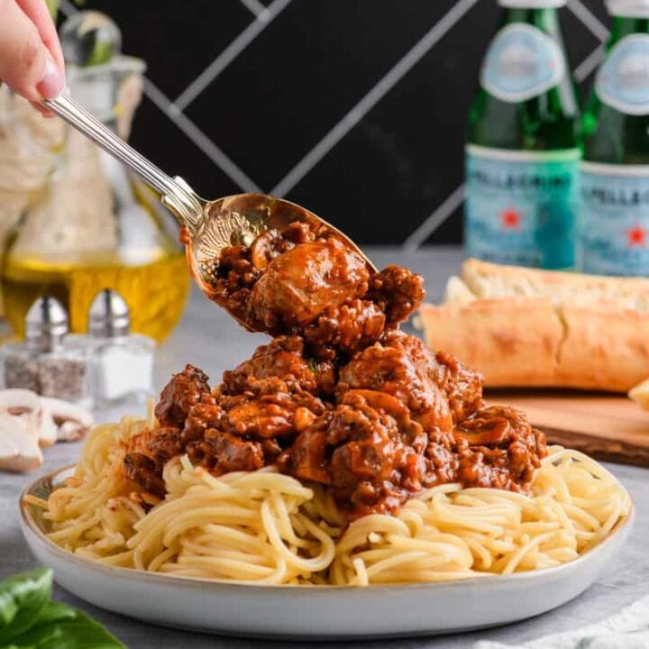 Sauce from Italian Sausage Spaghetti being spooned on top of pasta.